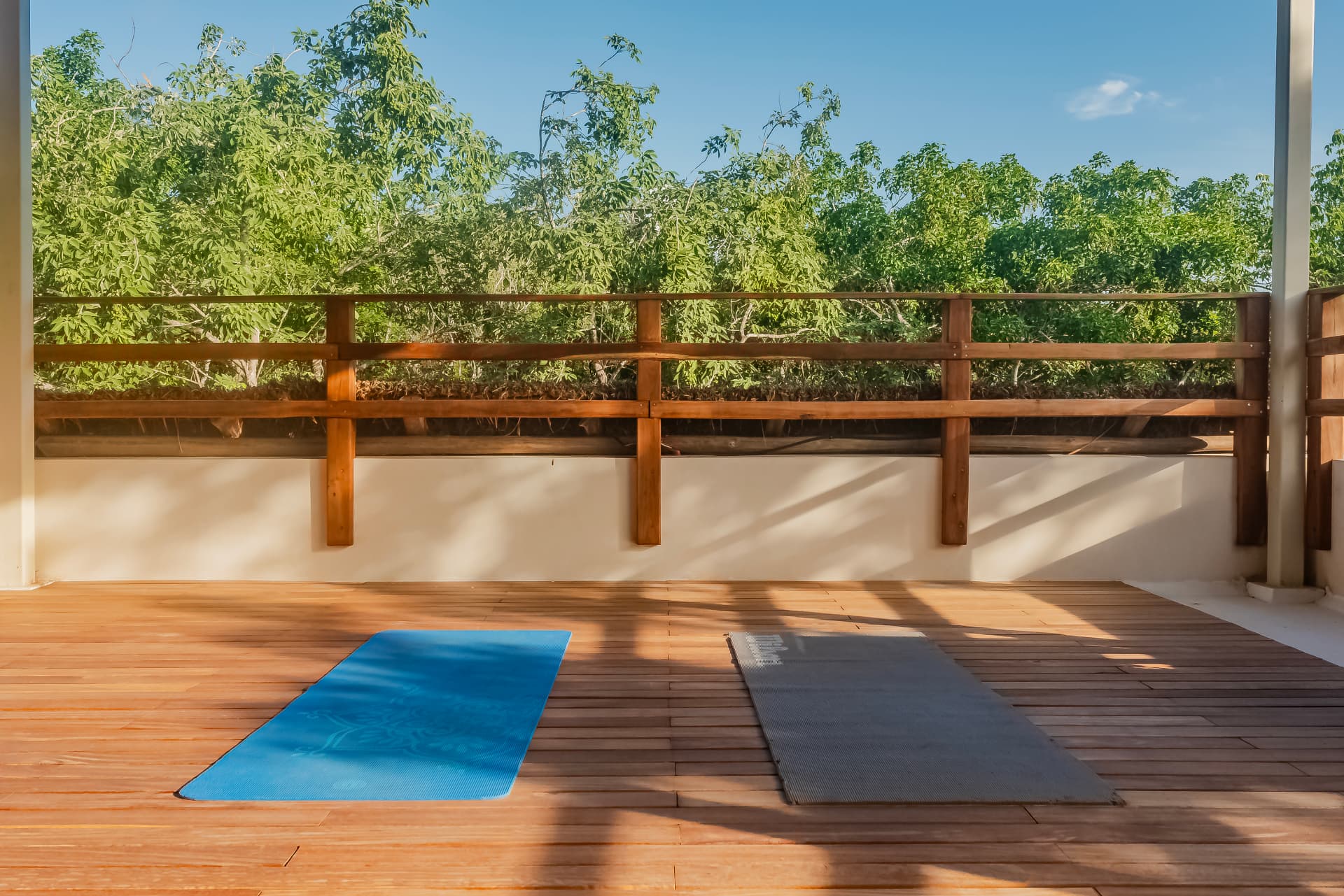 Rooftop teak yoga deck with two mats laid out facing the jungle