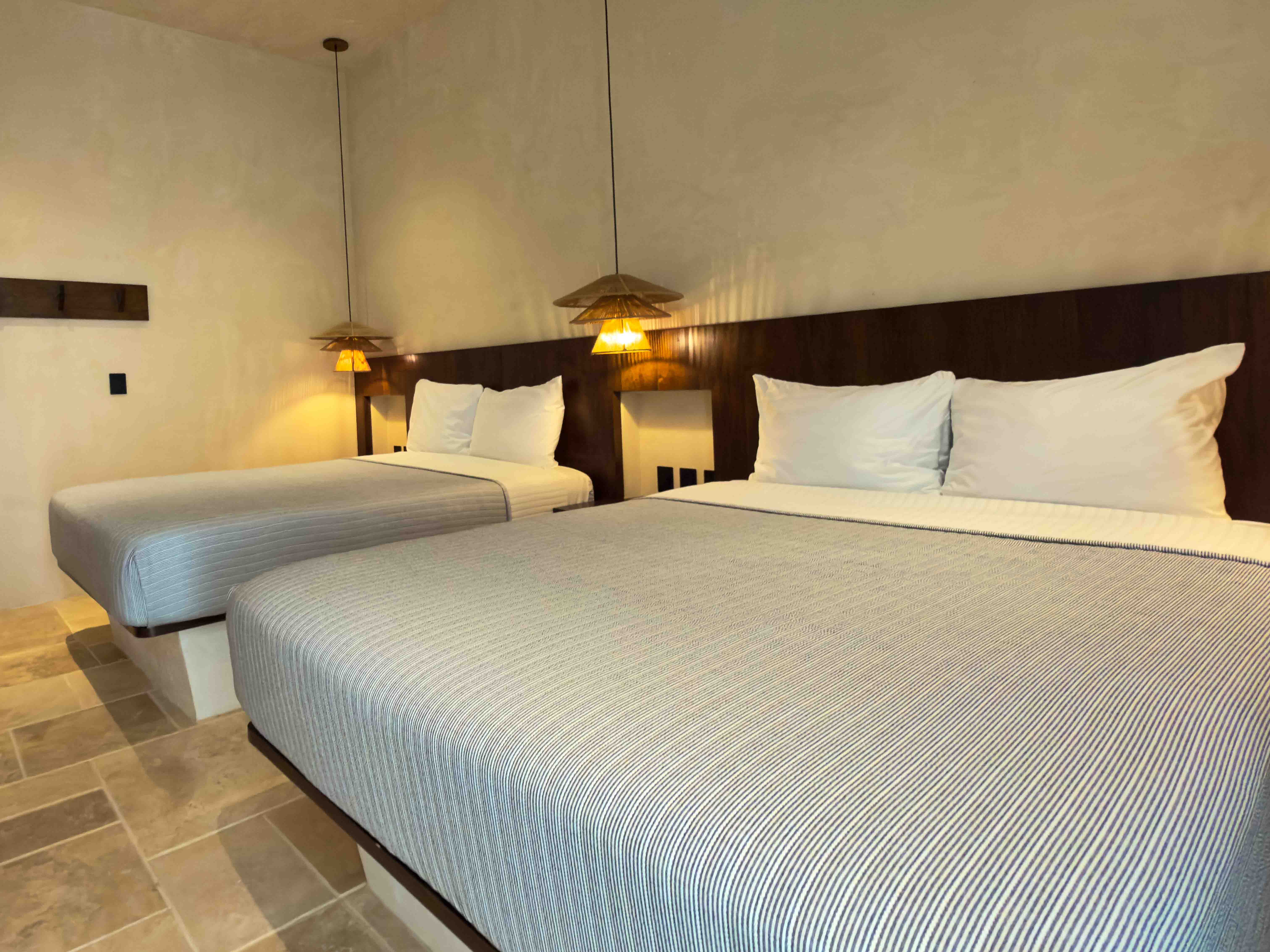 Twin-bed suite with warm pendant lighting and wood headboard